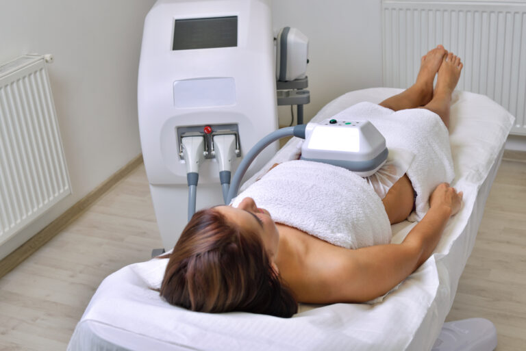 Beautiful young woman getting cryolipolyse treatment in cosmetic cabinet